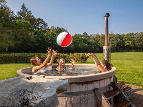 a group of people playing with a beach ball in a pool at Holiday Home Het Landhuis by Interhome in Losser