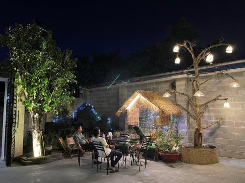un groupe de personnes assises à une table de patio la nuit dans l'établissement Khách Sạn K’My, à Ấp Phú Thọ