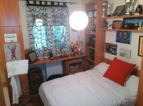 a bedroom with a bed and a desk and a window at Buenos Aires apartamento in Guadix