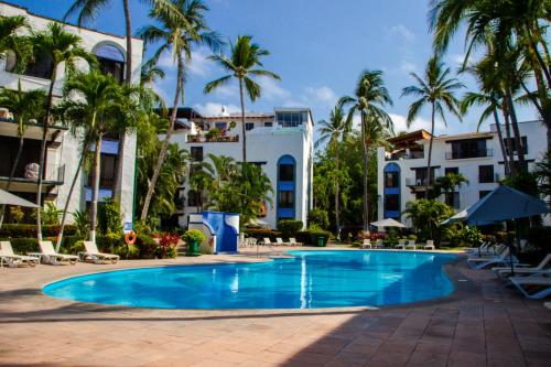 a swimming pool in front of a hotel with palm trees at Puerto de Luna Pet Friendly and Family Suites in Puerto Vallarta