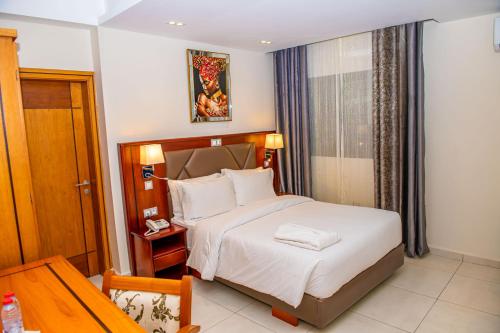 a hotel room with a bed and a table at Geneva Hotel in Douala