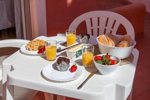 a white table with breakfast foods and orange juice at T - Casa Costa Doiro Guesthouse in Lagos