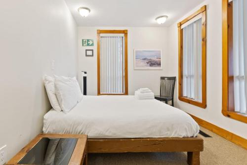 a bedroom with a bed with white sheets and windows at 3 Level Ski Chalet 7BR w Deck, Sauna & Ping-Pong! in Blue Mountains