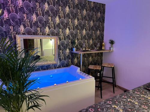 Habitación con bañera azul frente a un espejo. en La balnéo du Couvent, en Dijon