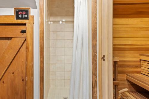 a shower with a white shower curtain in a bathroom at 3 Level Ski Chalet 7BR w Deck, Sauna & Ping-Pong! in Blue Mountains