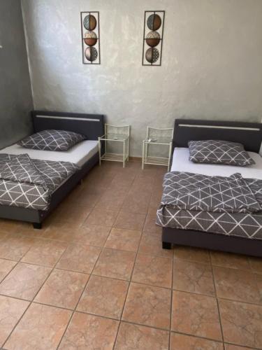 two beds in a room with a tiled floor at Haus Springpfuhl EG in Berlin
