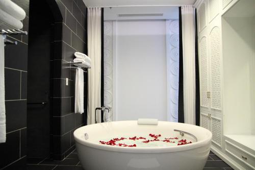 a bathroom with a white bath tub with red flowers on it at Chloe Gallery in Ho Chi Minh City