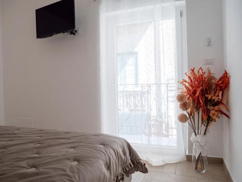 a bedroom with a bed and a window and a vase with flowers at Flower House in Santo Stefano di Camastra