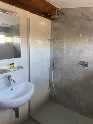 W łazience znajduje się umywalka i przeszklony prysznic. w obiekcie Hotel divino Amore w mieście Bagnoregio