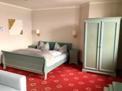 a bedroom with a green bed and a red carpet at Strandhotel Berg in Berg am Starnberger See