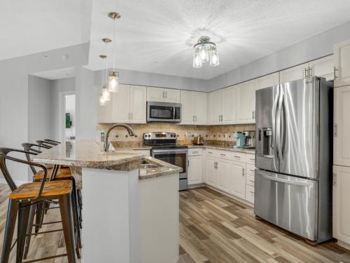 a kitchen with white cabinets and a stainless steel refrigerator at Blue Mountain Beach Condominium 102 by Newman-Dailey in Santa Rosa Beach