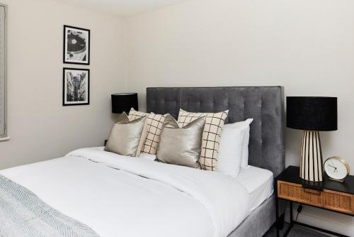 een slaapkamer met een groot bed met witte lakens en kussens bij The Elmbridge Getaway - Glamorous 2BDR with Garden in Londen