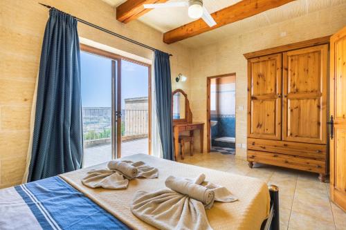 a bedroom with a bed and a large window at Ta Debora 3 bedroom Villa with private pool in Xagħra