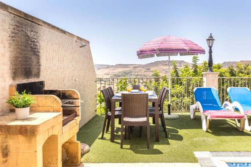 a patio with a table and chairs and an umbrella at Ta Debora 3 bedroom Villa with private pool in Xagħra