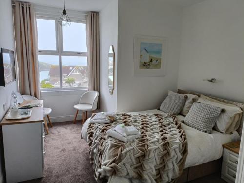 a bedroom with a bed and a desk and a window at Tregella Guest House in Newquay