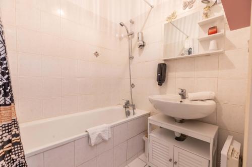 La salle de bains blanche est pourvue d'un lavabo et d'une baignoire. dans l'établissement Evasion Centre-ville 2 à 8 personnes, à Clermont-Ferrand