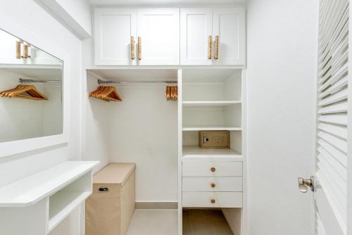 a walk in closet with white cabinets and a mirror at The Palms Resort in Saint James