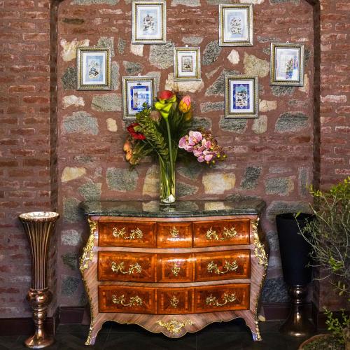 a dresser with a vase of flowers on a brick wall at Panderma Port Hotel in Bandırma