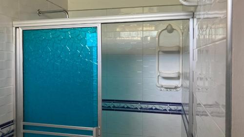 y baño con ducha y puerta de cristal azul. en Hotel El Broche en Yopal