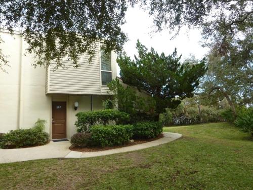 a white house with a door and a yard at Villas by The Sea Deluxe Two Bedroom Apartment in Jekyll Island