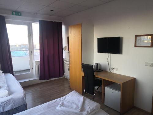 a hotel room with a desk and a bed and a bed and a room with at 101 Guesthouse Hotel in Reykjavík