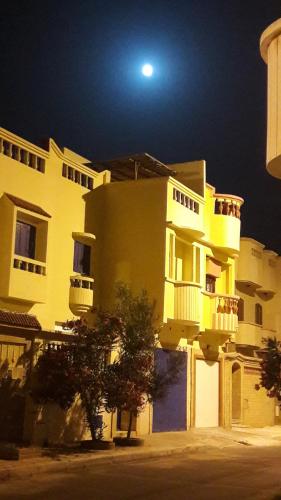 un gran edificio amarillo con una luna en el cielo en Taghart, la belle demeure, en Essaouira