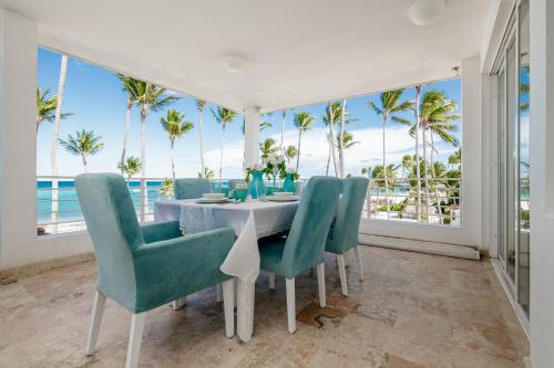 a dining room with a table and chairs and palm trees at Beachfront Punta Cana Condo for Rent - Ocean View, Private Terrace, and BBQ in Punta Cana