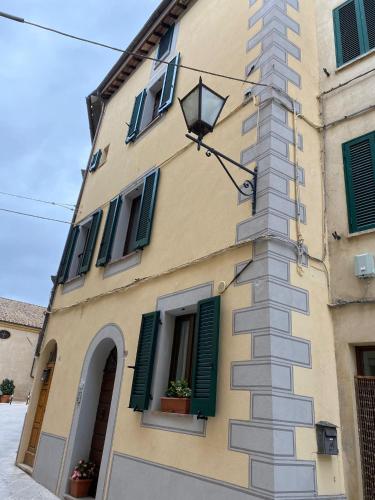 a yellow building with green shuttered windows and a street light at Il Terrazzino in Cetona