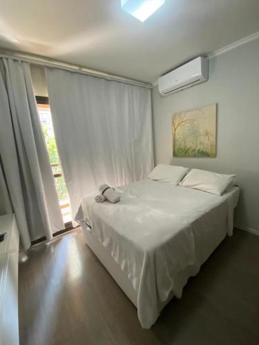 a bedroom with a large white bed and a window at Flat Avenida Paulista - Trianon in São Paulo