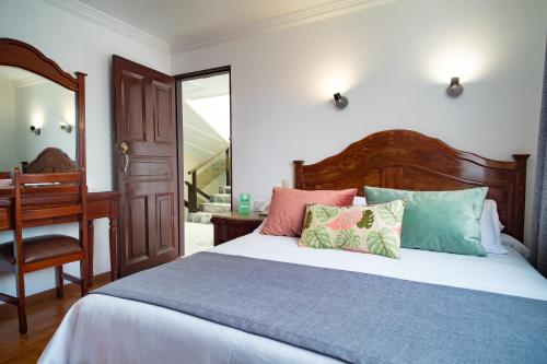 1 dormitorio con cama, silla y espejo en Hotel Virrey Central, en Bogotá
