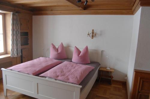 um quarto com uma cama com almofadas cor-de-rosa em Barrierefreie 3-Zi.-Ferienwohnung mit Gartenzugang in ruhiger, zentrumsnaher Lage em Oberammergau