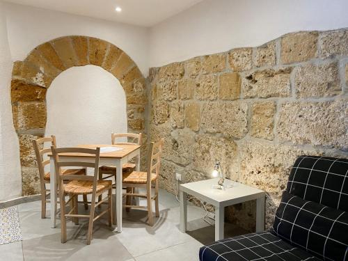 una sala da pranzo con tavolo, sedie e muro di mattoni di Nelle Antiche Mura a Castellammare del Golfo