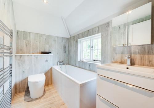 a white bathroom with a tub and a sink at The Hayloft in Dilham