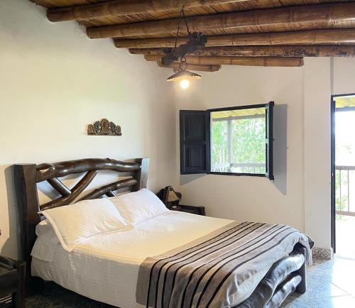 a bedroom with a large bed with a wooden headboard at Hotel Bosques Del Saman Alcala in Quimbaya