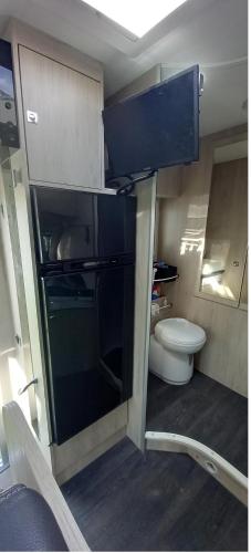a small kitchen with a toilet and a black refrigerator at Nuit en Camping car : une experience immersive in Segonzac