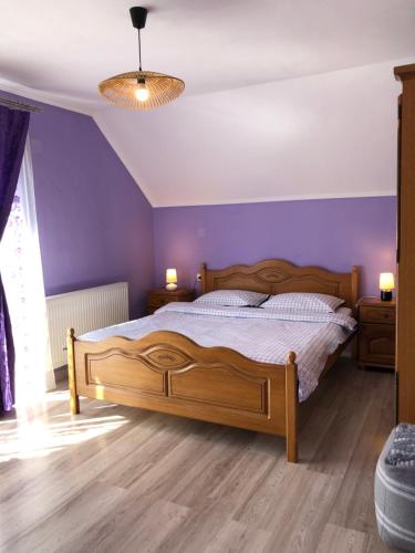 a bedroom with a wooden bed and purple walls at Casa Sofia in Călimăneşti