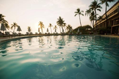 a large swimming pool with palm trees in the background at Mauna Kea Beach Hotel, Autograph Collection in Hapuna Beach