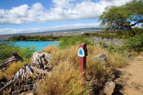a sign in the grass next to a body of water at Mauna Kea Beach Hotel, Autograph Collection in Hapuna Beach