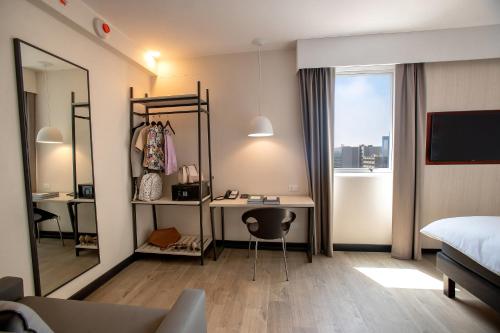 a bedroom with a desk and a bed and a mirror at ibis Styles Lima Benavides Miraflores in Lima
