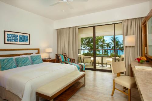 a hotel room with a bed and a balcony at Mauna Kea Beach Hotel, Autograph Collection in Hapuna Beach