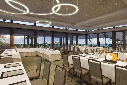 a restaurant with white tables and chairs and windows at Mauna Kea Beach Hotel, Autograph Collection in Hapuna Beach