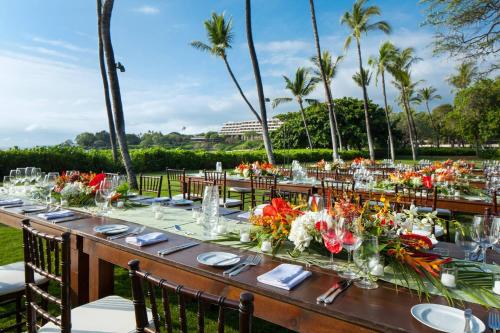 a long table with flowers on it with palm trees at Mauna Kea Beach Hotel, Autograph Collection in Hapuna Beach