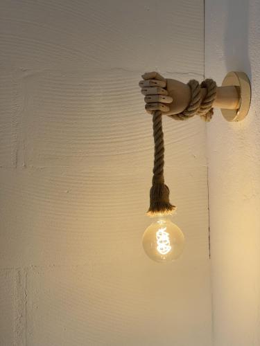 a light hanging from a wall with a hand holding a bulb at Insolite : Gîte Namaste à 500m à pied du Zoo de Beauval in Seigy