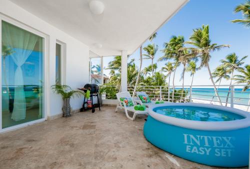 a house with a tub on a balcony with the ocean at Beachfront Punta Cana Condo for Rent - Ocean View, Private Terrace, and BBQ in Punta Cana