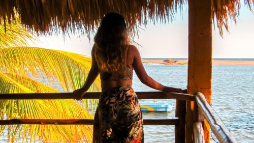 a woman standing on a porch looking at the ocean at Hotel Restaurante Spa La Barca de Oro in Las Peñitas