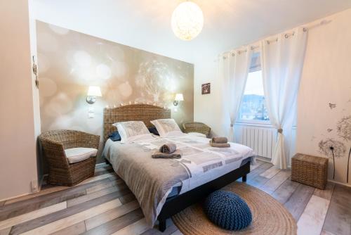 a bedroom with a large bed and wicker chairs at Gîte l'Améthyste 3 appartements in Gérardmer