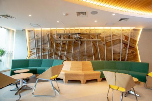 una sala de espera con un sofá verde y sillas en ibis Styles Lima Benavides Miraflores, en Lima