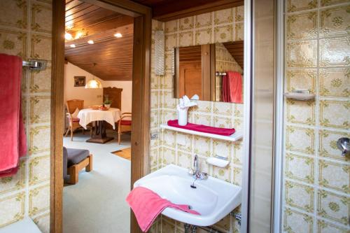 ein Bad mit einem Waschbecken und ein Zimmer mit einem Tisch in der Unterkunft Haus St. Korbinian in Mittenwald