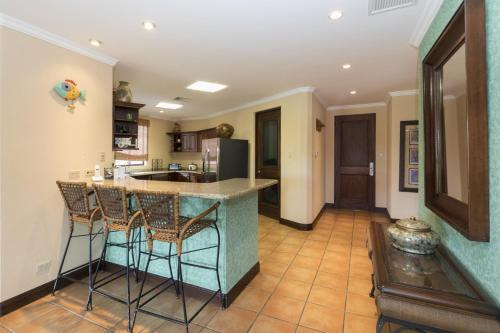 Una cocina con encimera y taburetes en una habitación. en Bougainvillea 5306 Luxury Apartment - Reserva Conchal, en Playa Conchal