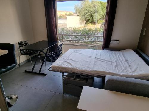um quarto com uma cama e uma janela com uma mesa em Studio climatisée dans résidence à 5 minutes des plages a pied em Propriano